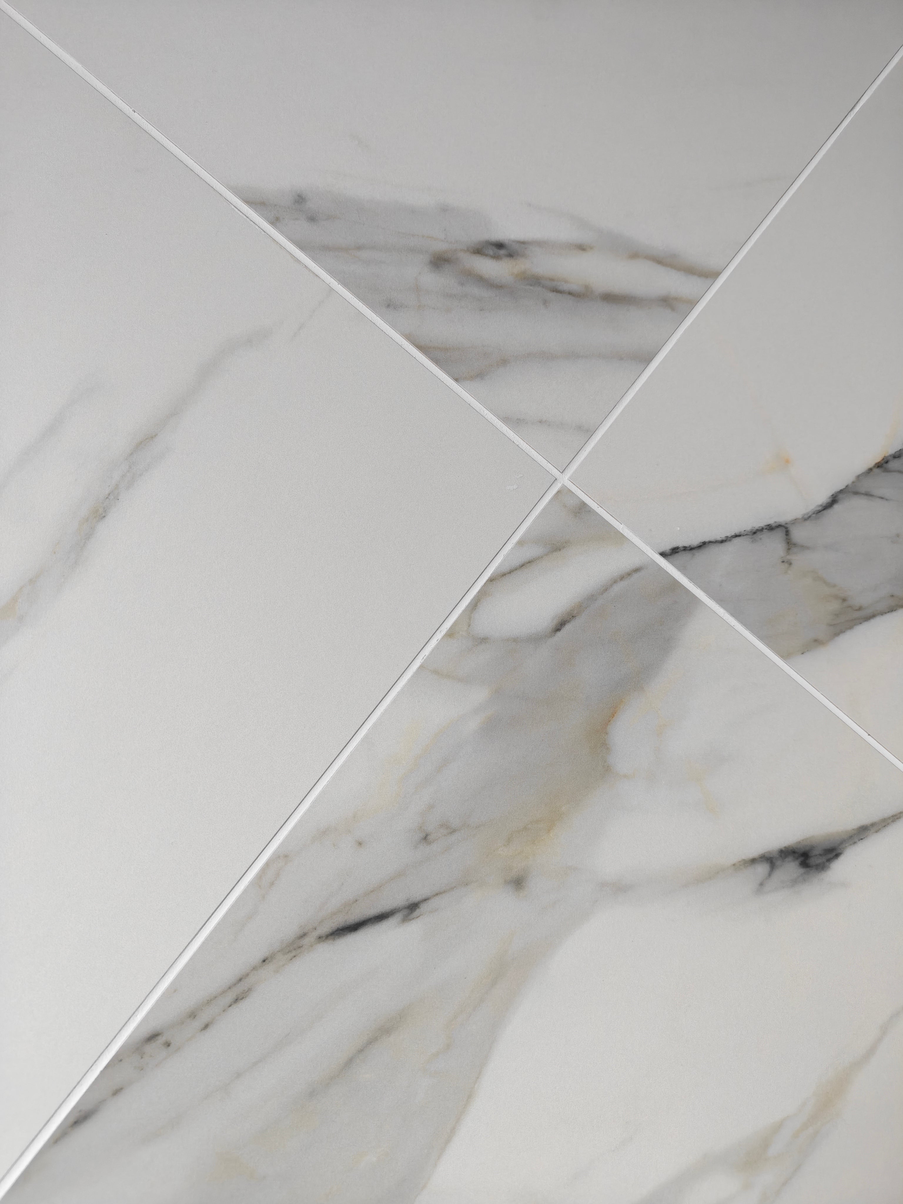 Calacatta Oro Matt tile showcasing elegant grey veining and warm golden accents on a soft white surface.