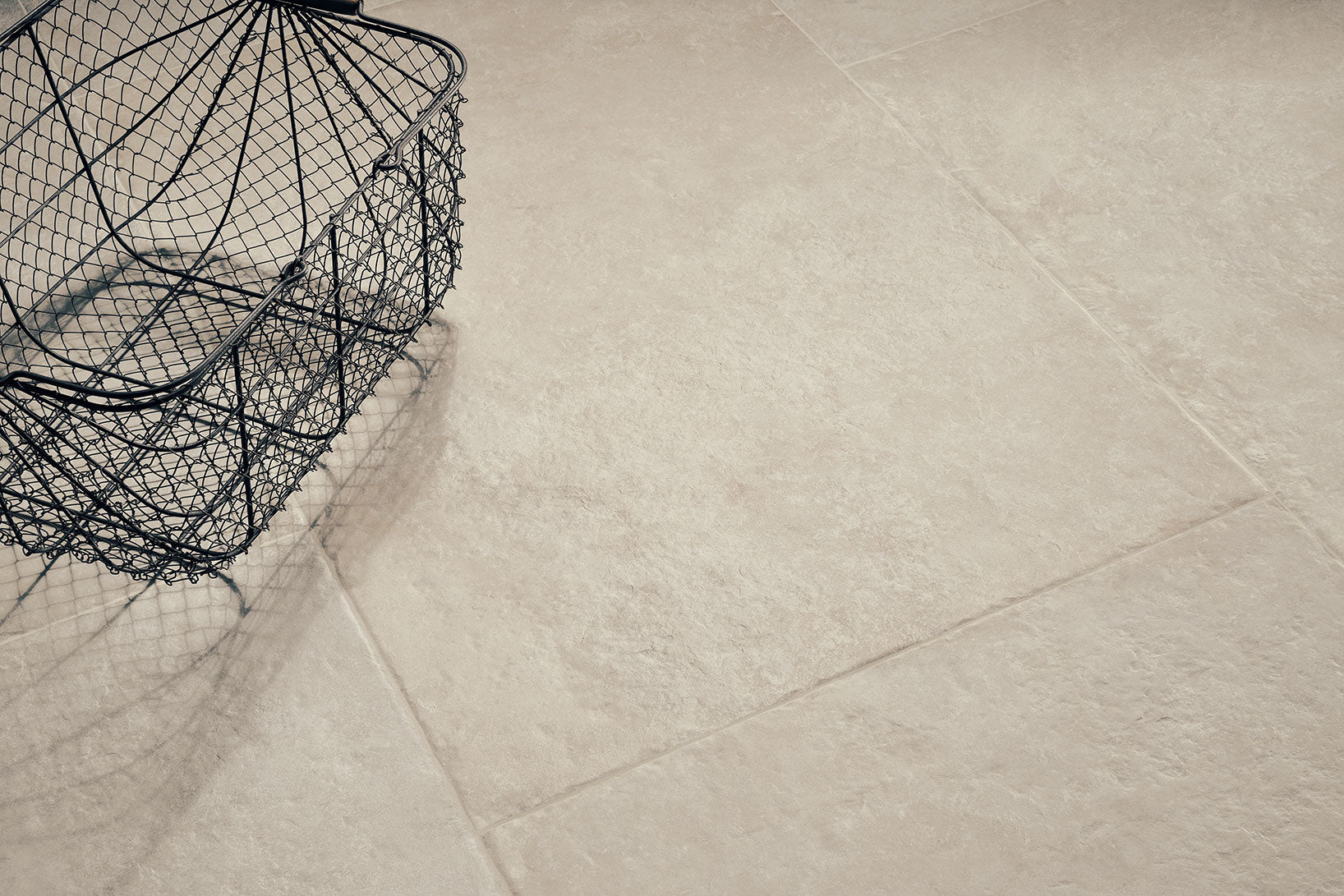 Castleton Ivory porcelain tiles featuring a subtle stone-like texture and a decorative wire basket.