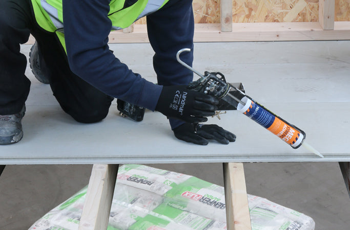 Person applying adhesive to STS TG4 Cement Board 22mm during installation process on a construction site.